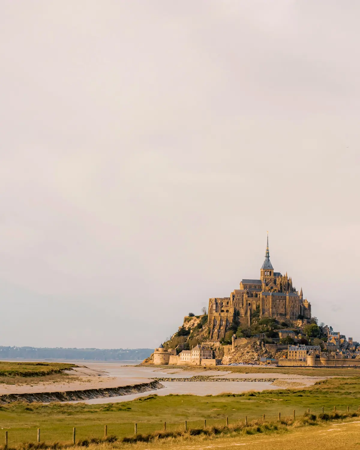 Mont-Saint-Michel at low tide, the bay drained to sand and grass around the granite rock